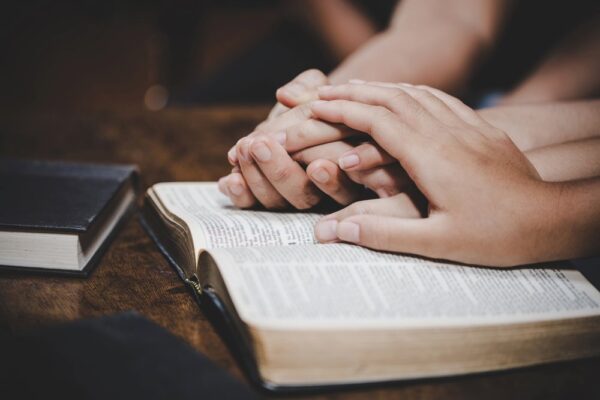 A hand comforts another set of hands on a Bible